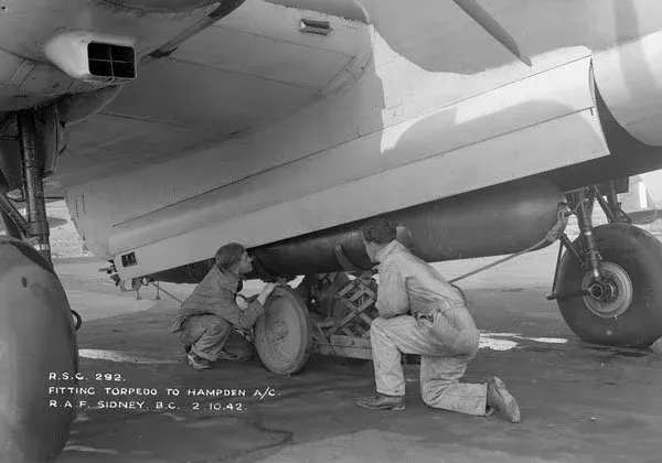 Groundcrew loading a torpedo into the bomb bay of a Handley Page Hampden I aircraft of No. 32 Operational Training Unit, RCAF, Patricia Bay, British Columbia, 2 October 1942