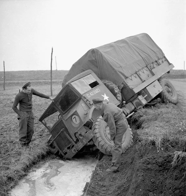 Personnel of the Royal Canadian Corps of Signals (R.C.C.S.), 2nd Canadian Infantry Division, examining a Ford three-ton truck which sank into a ditch