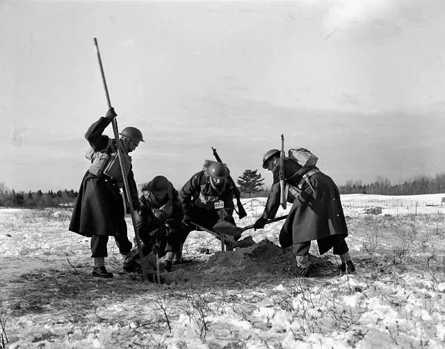 Members of a demolition squad fill a hole planted with 90 pounds of RDX explosives before a field test at Petawawa Military Camp