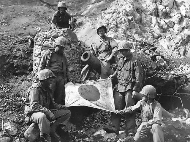 U.S. Marines pose with a captured Japanese flag on top of an enemy pillbox at Iwo Jima