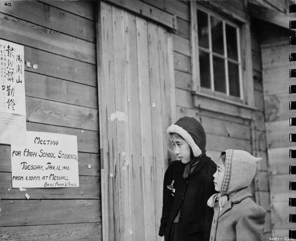 Japanese-Canadian girls reading signs outside the school at an internment camp