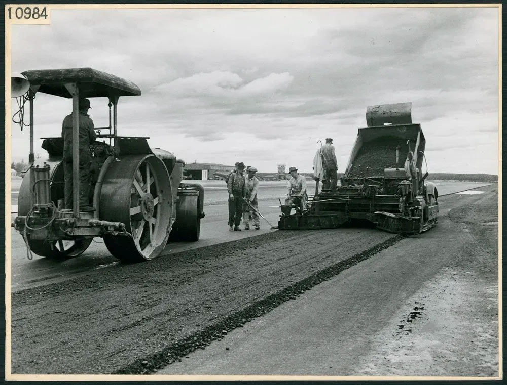 Civilian workers lay runway strips of asphalt as part of the Northwest Staging Route operations at Watson Lake