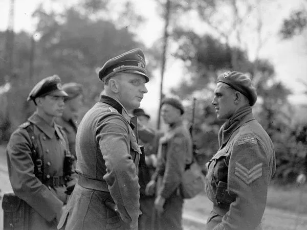 Sergeant H.A. Barnett of the Canadian Army Film and Photo Unit talking with a German officer during the surrender of German troops at Herquelingue near Boulogne, France, 21 September 1944