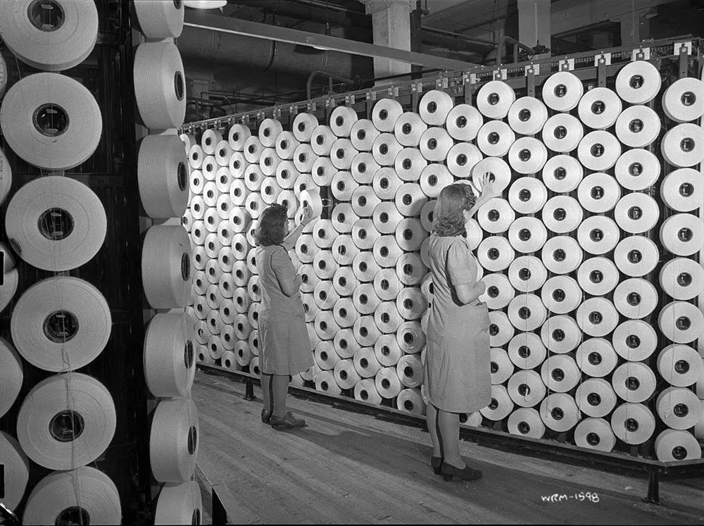Women workers adjust spools of cotton yarn at the Montreal Cottons Textile factory, Valleyfield, Quebec