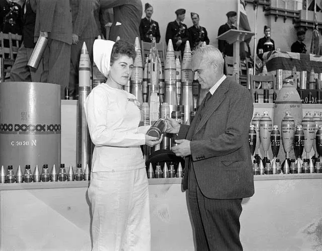 Edna Poirier, female worker of the Defence Industries Limited plant, presents the 100,000,000th projectile to Hon. C.D. Howe at the Cherrier plant