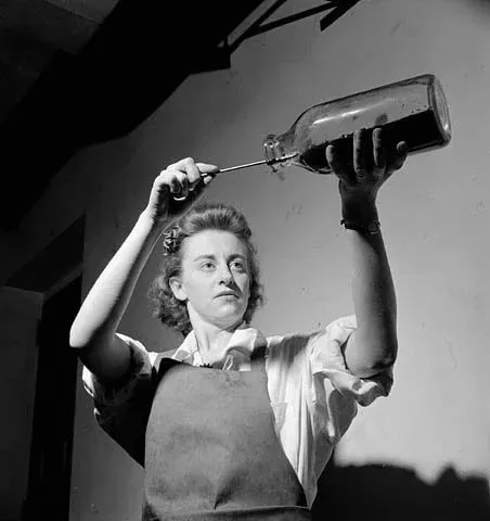 Woman worker empties a bottle containing penicillin mould during penicillin production at the Connaught Labs