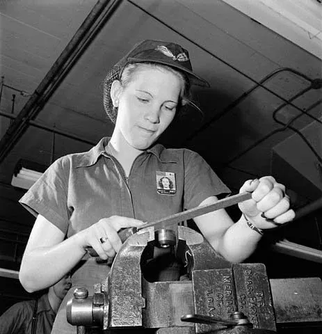 Woman factory worker files a machine part