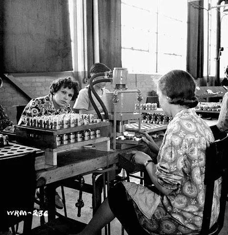Women workers examine and measure fuses in a Canadian manufacturing plant